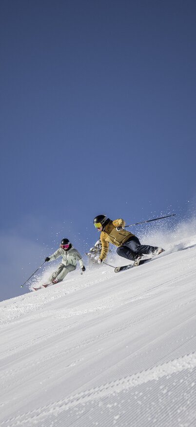 Zwei Skifahrer auf der Planai, Schladming bei blauem Himmel und Sonnenschein | © Mirja Geh